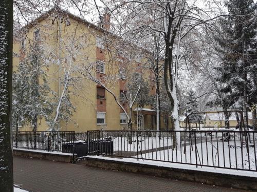 a black fence in front of a yellow building at Lia Apartman in Kiskunhalas