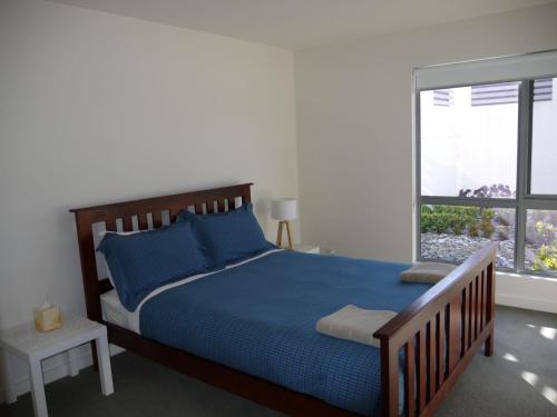 Un dormitorio con una cama azul y una ventana. en Spectacular Holiday Living, en Bridport