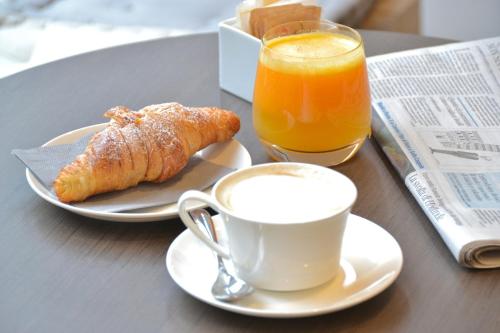 a table with a cup of coffee and a croissant and orange juice at Hotel Katty in Rome