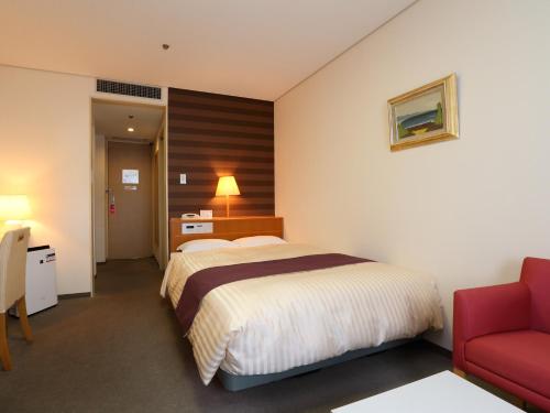 a hotel room with a bed and a red chair at Fukuoka Recent Hotel in Fukuoka