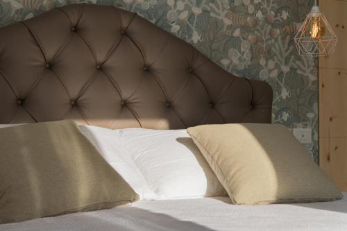 a bed with a brown headboard and two pillows at Lainez Rooms & Suites in Trento