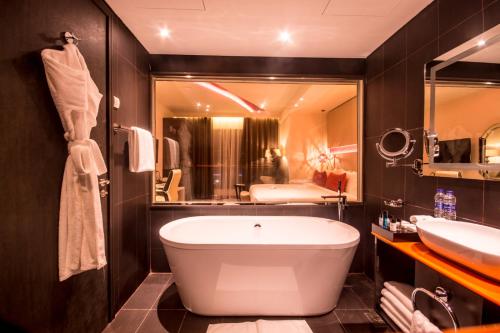 a bathroom with a tub and a large mirror at Carnelian by Glory Bower Hotels in Muscat