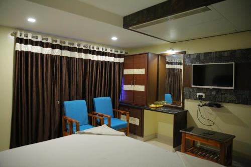 Un dormitorio con una cama, un escritorio y un televisor. en Hotel Siddhartha, en Guntūr