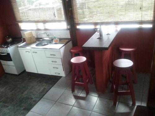 una cocina con 3 taburetes rojos y un fregadero en Tacama, en La Pedrera