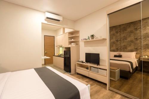 a hotel room with a bed and a television at Treehouse Suites - Boutique Serviced Apartment in Jakarta