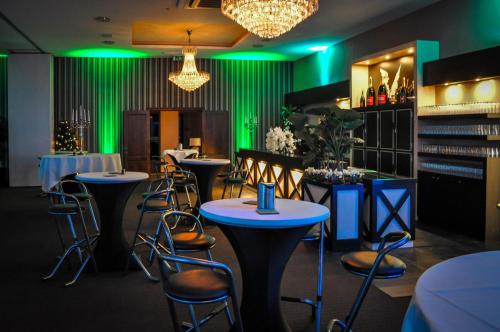 a restaurant with green lighting and tables and chairs at De Vesten Comfort Lodge in Laakdal