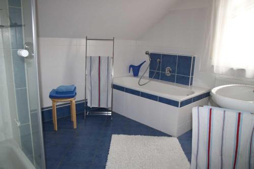 een blauwe en witte badkamer met een bad en een wastafel bij Haus Köberle Ummendorf in Biberach-Ummendorf