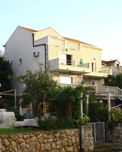 a large house with a stone fence in front of it at Apartments Miljas in Cavtat