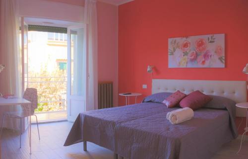 コゼンツァにあるB&B Rosaの赤い壁のベッドルーム1室、ピンクの枕付きのベッド1台が備わります。