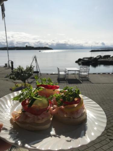 a plate with two sandwiches on a table near the water at Sjøberg Hotell og Ferie Leiligheter in Østhusvik