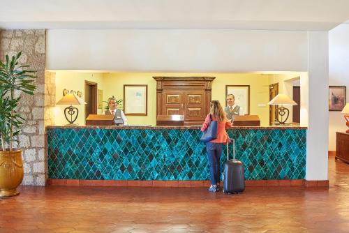 
a woman standing in front of a green wall in a kitchen at Penina Hotel & Golf Resort in Portimão

