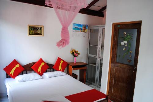 a bedroom with a bed with red and white pillows at Evening Star Guest Inn in Kandy