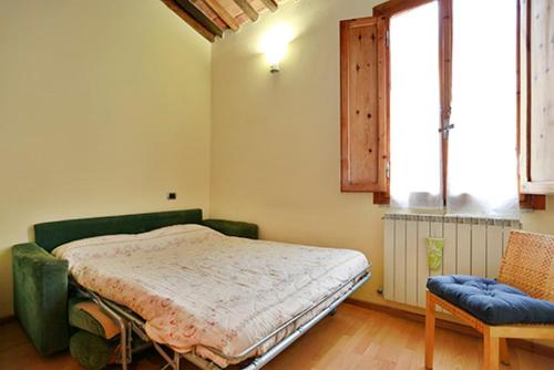 a bedroom with a bed and a chair and a window at Casa Alberto in Lucca