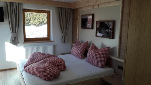 a small bedroom with a bed with red and white pillows at Gasthof Leiter´s Hoamatl in Umhausen