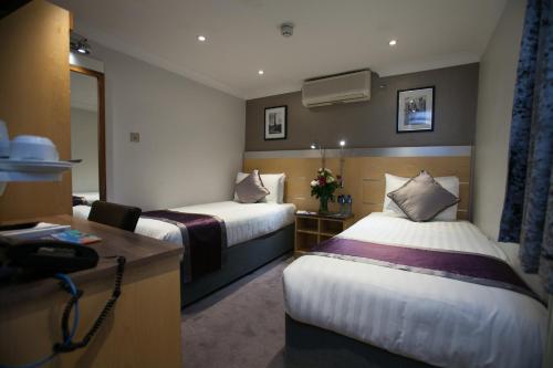a hotel room with two beds and a desk at Best Western Victoria Palace in London