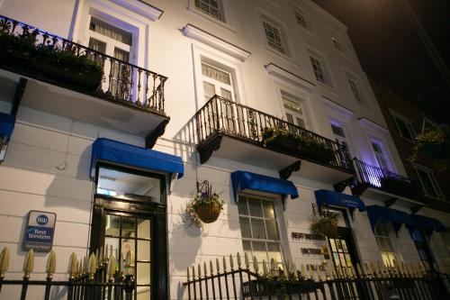 a white building with balconies and plants on it at Best Western Victoria Palace in London