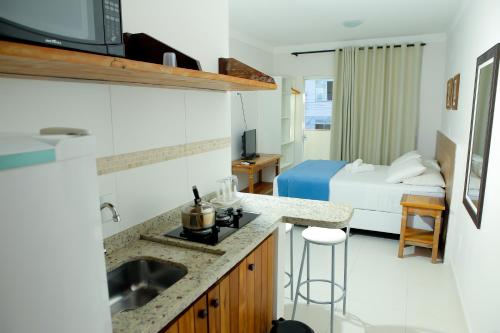1 dormitorio con 1 cama y baño con lavabo. en Pousada Águas de Bombinhas, en Bombinhas