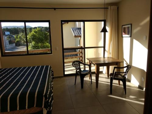 een slaapkamer met een bed, een tafel en stoelen bij Studios Formanabá in Florianópolis