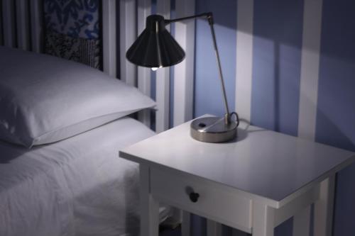 a lamp on a table next to a bed at Door Eight in Il-Furjana