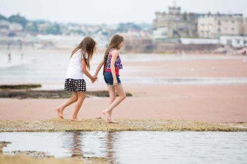 two young girls walking on the beach at The Osborne Apartments in Torquay