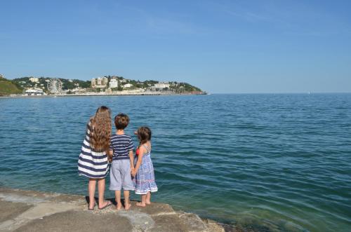 a woman and two children standing on a rock near the water at The Osborne Apartments in Torquay