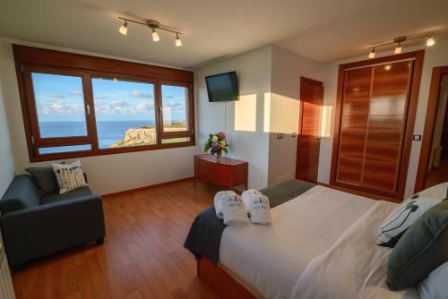 OviñanaにあるMirador del Marのベッドルーム1室(ベッド1台、椅子、窓付)