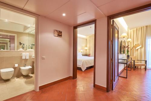 a bathroom with a toilet and a bedroom with a bed at Penina Hotel & Golf Resort in Portimão