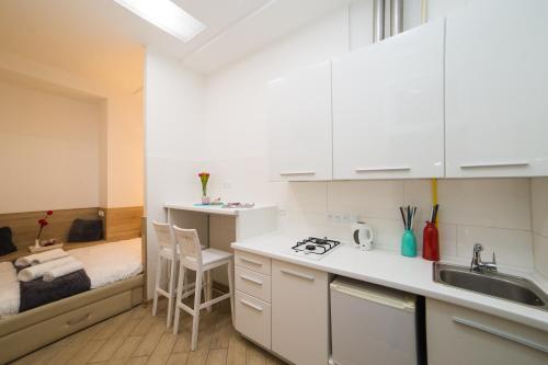 een keuken met witte kasten, een wastafel en een bed bij Mini Economy apartments in the central part of Lviv- Krekhivska 7 in Lviv