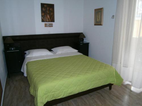 a bedroom with a large bed with a green comforter at Antonios Rooms in Akrata