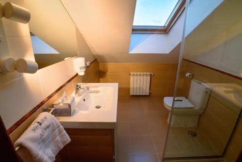 a bathroom with a sink and a toilet and a skylight at Mirador del Mar in Oviñana
