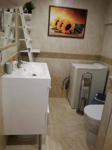 a bathroom with a sink and a toilet and a painting of a sunflower at Apartamentai Klonio g. in Druskininkai