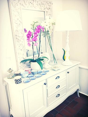 a white dresser with a mirror and flowers on it at Oude Berg Guesthouse - 10 Caledon Street in George