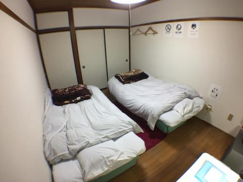 2 bedden in een kleine kamer met witte lakens bij Kenroku Haitsu 202 in Kanazawa