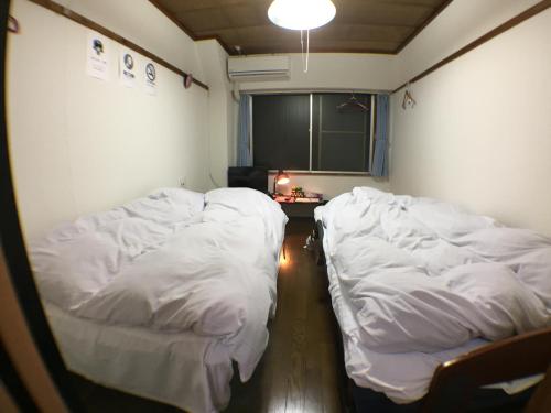 2 camas en una habitación con sábanas blancas en Kenroku Haitsu 302, en Kanazawa