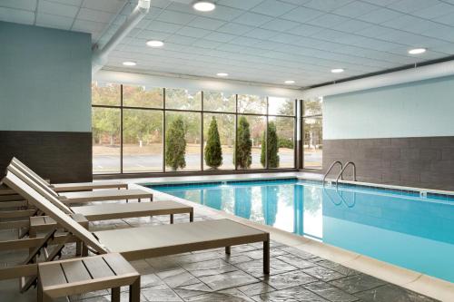 a swimming pool with chairs and a swimming pool at Radisson Akron-Fairlawn Copley in Fairlawn