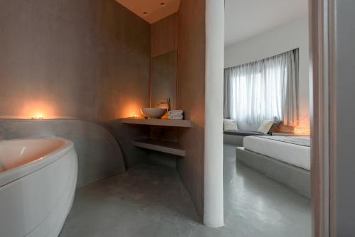 a bathroom with a tub and a sink and a bed at Anemomilos in Oia