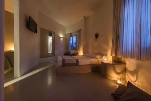 a bedroom with a bed and a window with blue curtains at Anemomilos in Oia