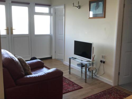 a living room with a couch and a television at Pebble Lodges in Gurnard