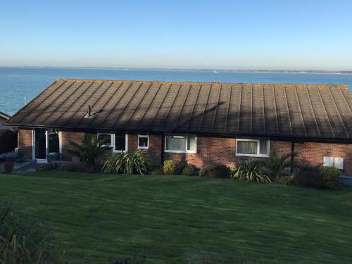 a house with an old tin roof on a lawn at Pebble Lodges in Gurnard