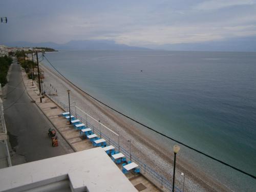 a beach with blue and white umbrellas and the ocean at Antonios Rooms in Akrata