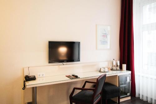 a room with a desk with a tv and a chair at Hotel Prens Berlin in Berlin