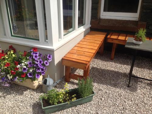 a wooden bench sitting next to a window with flowers at Denton House Hostel in Keswick