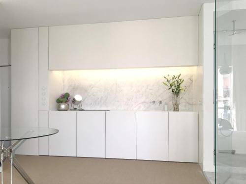 a kitchen with white cabinets and a glass table at New Loft - Lisboa Estrela in Lisbon