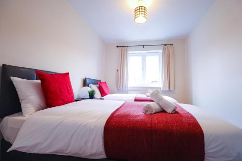 a bedroom with two beds with red and white pillows at Royal Oak Home in Wythenshawe