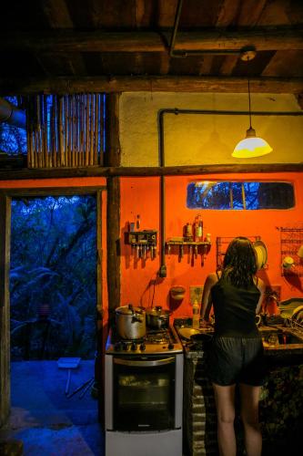a woman standing at a stove in a kitchen at Remo Hostel in Parati-Mirim