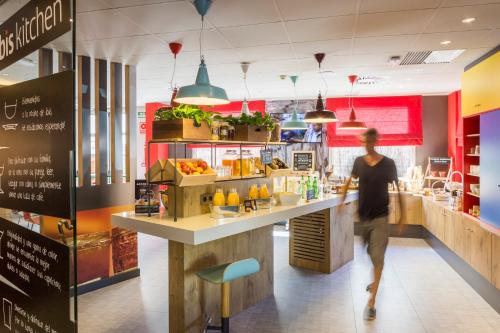 a man walking past a counter in a fast food restaurant at Ibis Barcelona Castelldefels in Castelldefels