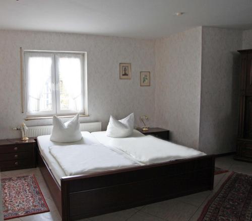 a bedroom with a bed with white sheets and a window at Hotel Landhaus Köln in Lindlar