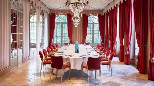 a large dining room with a long table and red curtains at Brenners Park Hotel & Spa, Oetker Hotels in Baden-Baden