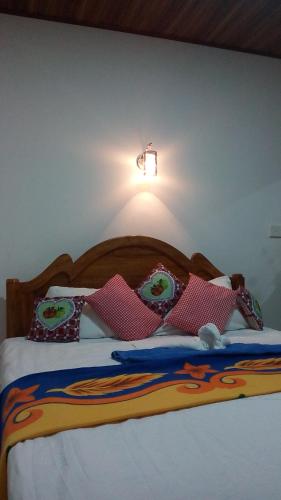 a bed with pillows and a light on the wall at Milan Home Stay in Ella