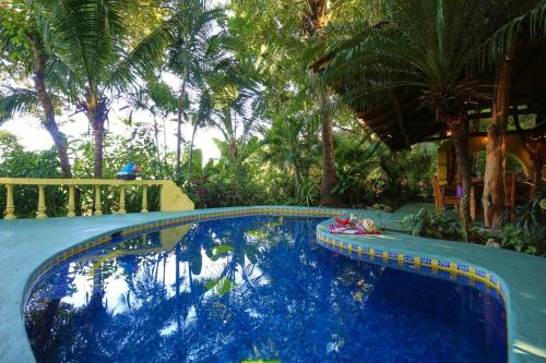 a swimming pool in a yard with palm trees at Nosara Sunrise Bed and Breakfast in Nosara